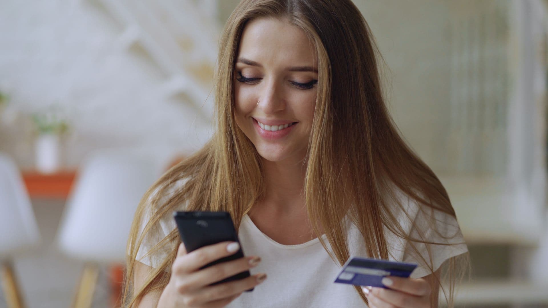 Cliente comprando pelo celular com o cartão na mão